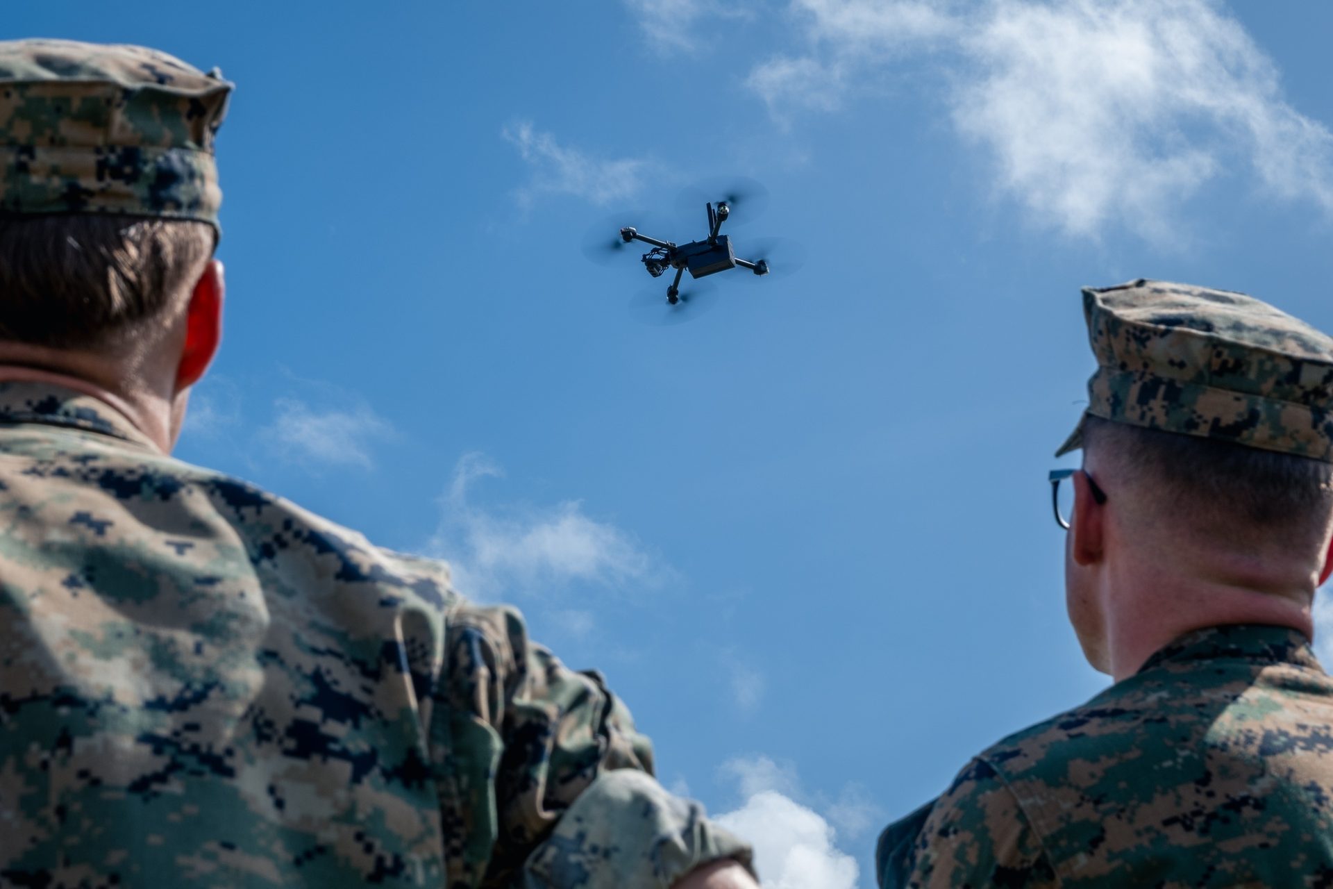 Two U.S. Marines watching a small quadcopter overhead